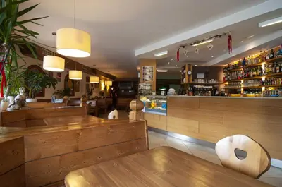 a restaurant with wooden tables and chairs and a bar at Albergo Antelao in San Vito di Cadore