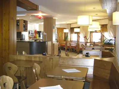 a restaurant with wooden tables and chairs and a counter at Albergo Antelao in San Vito di Cadore