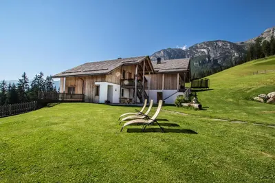a chair sitting on a lawn in front of a house at Agriturismo Maso Runch in Badia