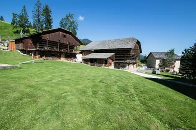 a large green field in front of two barns at Agriturismo Maso Runch in Badia