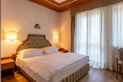 a bedroom with a bed and a large window at Hotel Sporting in Val di Zoldo