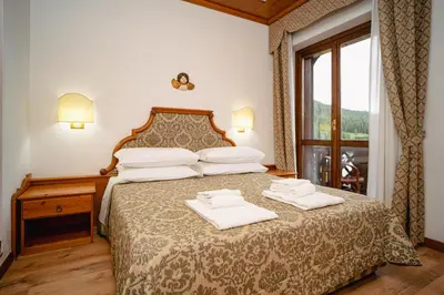 a bedroom with a bed with two towels on it at Hotel Sporting in Val di Zoldo
