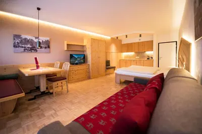 a bedroom with a bed and a desk and a kitchen at Apartment Lilli mit Garagenstellplatz in Bressanone