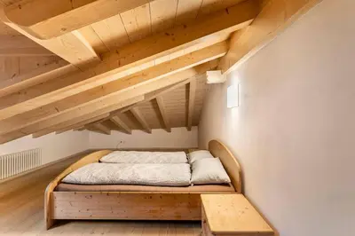 a bed in a room with a wooden ceiling at Appartamento rustico con stube e balcone in Predazzo