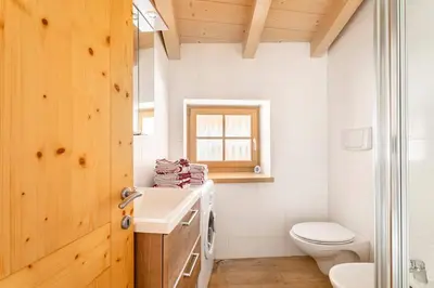 a bathroom with a white toilet and a sink at Appartamento rustico con stube e balcone in Predazzo