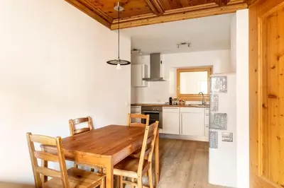 a kitchen with a wooden table and chairs in a room at Appartamento rustico con stube e balcone in Predazzo