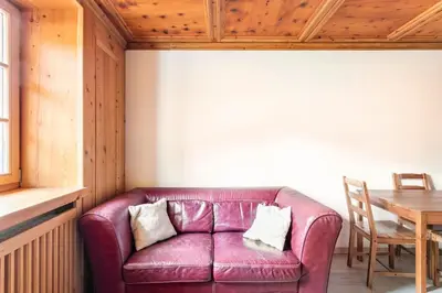 a purple leather couch in a room with a table at Appartamento rustico con stube e balcone in Predazzo