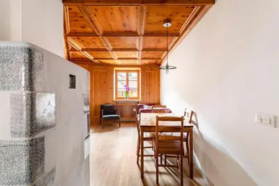 a dining room with a table and chairs and a window at Appartamento rustico con stube e balcone in Predazzo