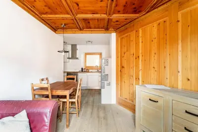 a kitchen and dining room with a wooden ceiling at Appartamento rustico con stube e balcone in Predazzo