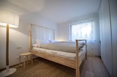 a bedroom with a bed with a wooden frame and a window at Apartment Lulu in Selva di Val Gardena