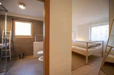 a bedroom with a bed and a bathroom with a toilet at Apartment Lulu in Selva di Val Gardena