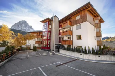 an apartment building in the mountains with a parking lot at Apartment Lulu in Selva di Val Gardena