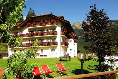 a large building with red chairs in front of it at Hotel Plank in San Martino di Castrozza