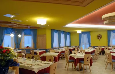 a restaurant with tables and chairs and blue curtains at Hotel Plank in San Martino di Castrozza