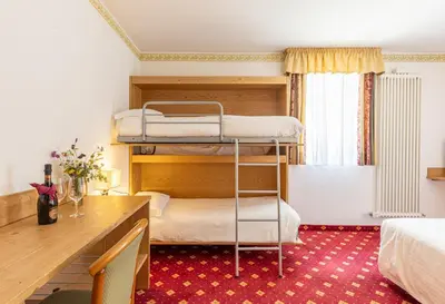 a room with two bunk beds and a desk at Hotel Plank in San Martino di Castrozza