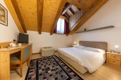 a bedroom with a bed and a desk with a computer at Hotel Plank in San Martino di Castrozza