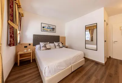 a bedroom with a large white bed in a room at Hotel Plank in San Martino di Castrozza