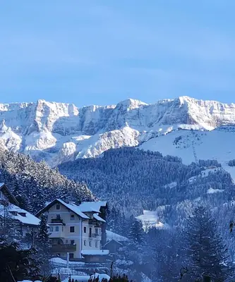 a snow covered mountain range with a house in the foreground at ATI Appartamento stile Chalet dell 800 nel cuore di Ortisei in Ortisei