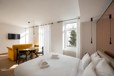 a bedroom with a white bed and a table at Guesthouse diWINE in Merano
