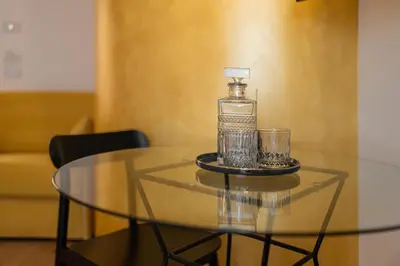 a glass table with a bottle and glasses on it at Guesthouse diWINE in Merano