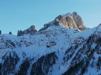 a mountain covered in snow with a blue sky at Tana delle Marmotte in Falcade