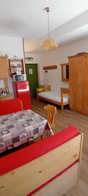 a living room with a table and a kitchen and a room at Tana delle Marmotte in Falcade