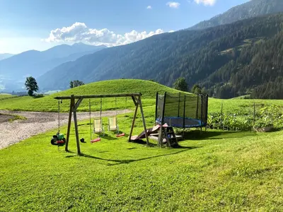a person sitting on a swing in a field at Schneiderhof, Chalet, Urlaub auf dem Bauernhof in Ridanna