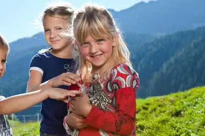 a young girl holding a bird in her hands at Schneiderhof, Chalet, Urlaub auf dem Bauernhof in Ridanna