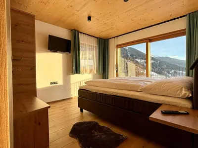 a bedroom with a bed and a large window at Schneiderhof, Chalet, Urlaub auf dem Bauernhof in Ridanna