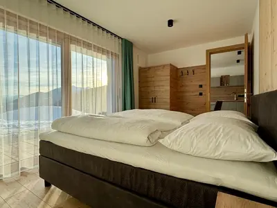 a bedroom with a large bed with a large window at Schneiderhof, Chalet, Urlaub auf dem Bauernhof in Ridanna