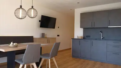 a kitchen with a table and chairs and a balcony at Runk Apartments in Siusi