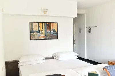 two beds in a room with a painting on the wall at Villa Tivoli in Merano