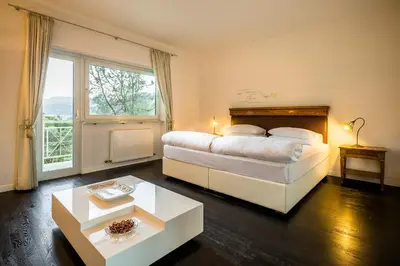 a bedroom with a large bed and a large window at Villa Tivoli in Merano