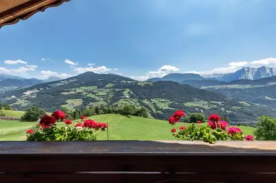 an aerial view of a green hill with mountains at HAUSERHOF Farmhouse with Dolomite View in Villandro