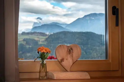 two chairs and a table on a patio with mountains at HAUSERHOF Farmhouse with Dolomite View in Villandro
