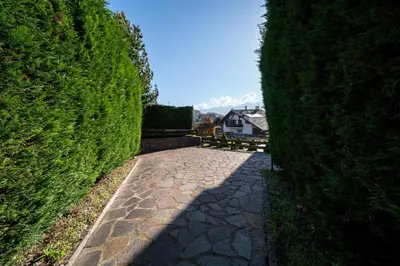 a path between two hedge hedges with a house in the background at Casa Gialla in Varena