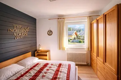 a bedroom with a bed with a gray wall at CASA 4 PIOPPI - 2 camere, balcone, garage Dolomiti Affitti in Cavalese