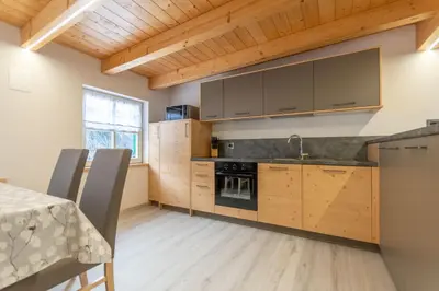 a kitchen with wooden cabinets and a table with chairs at Chalet Butterfly 3 in Mazzin