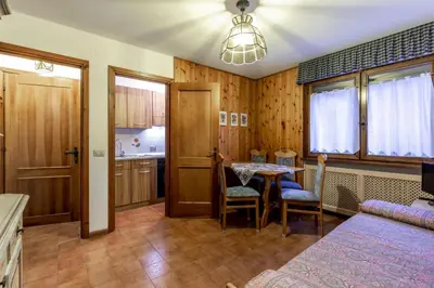 a room with a bed and a table and a kitchen at Des Alpes 3 in Canazei