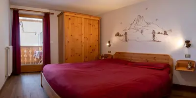 a bedroom with a large white bed and a window at Casa Davarda in Vigo di Fassa