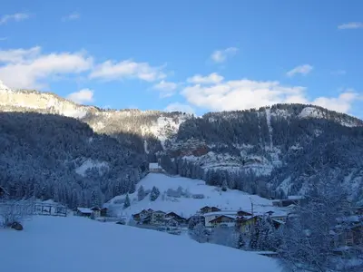 a bedroom with two beds and a chair at Casa Davarda in Vigo di Fassa