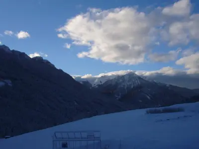 a snow covered hill with houses and a mountain at Casa Davarda in Vigo di Fassa