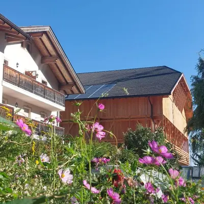 a building with a fence and flowers in front of it at Planitzhof in Castelrotto