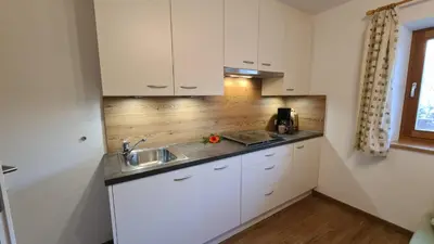 a kitchen with white cabinets and a sink at Planitzhof in Castelrotto