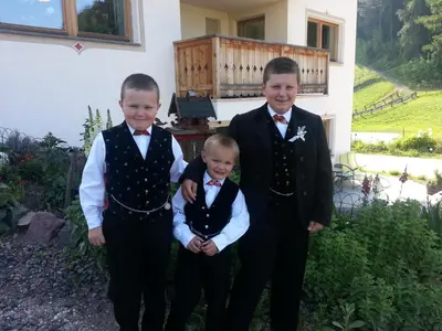 three boys dressed in tuxedos posing for a picture at Planitzhof in Castelrotto