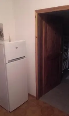 a white refrigerator in a room with a door at B&B Signora Elvira in Capriana