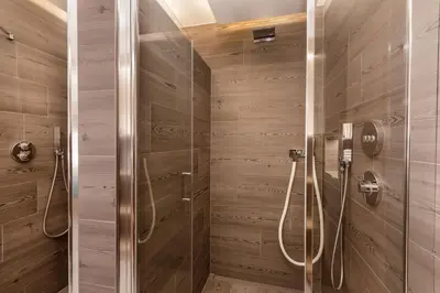a shower stall in a bathroom with wooden walls at Apartments Pragser Wildsee - by Familiaris in Braies