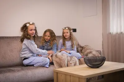 three girls sitting on a couch in a living room at Apartments Pragser Wildsee - by Familiaris in Braies