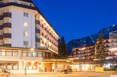 a large building with snow in front of it at Hotel Alaska Cortina in Cortina dʼAmpezzo
