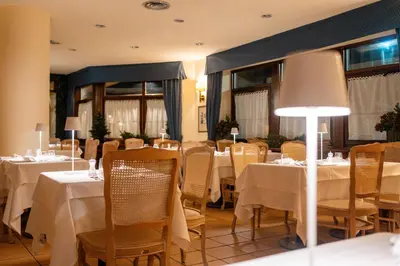 a dining room with tables and chairs with white table linen at Hotel Alaska Cortina in Cortina dʼAmpezzo